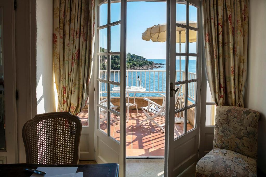 an open door to a patio with a view of the ocean at Hotel Le Maquis in Porticcio