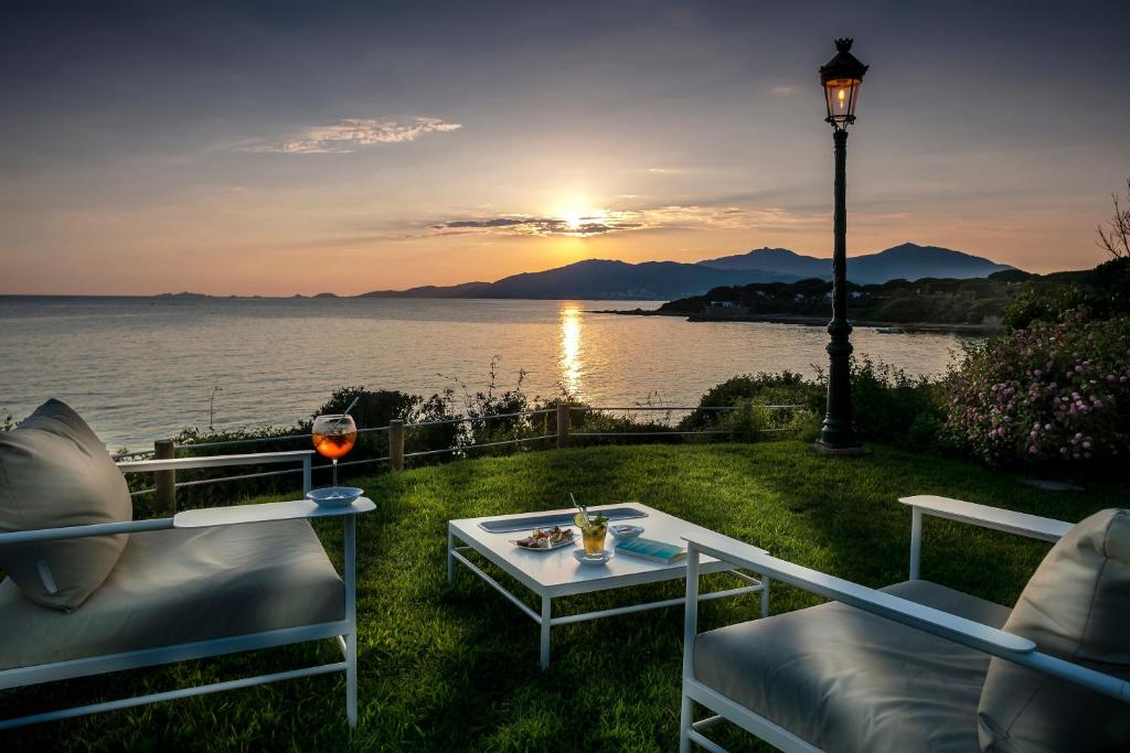 a table with a glass of wine and a light pole at Hotel Le Maquis in Porticcio