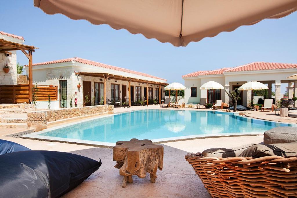 a large swimming pool with chairs and an umbrella at Casa Afytos - Adults Only in Afitos