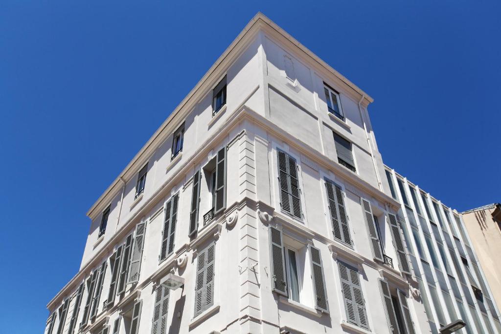 a white building with windows on a blue sky at Hôtel P.L.M. in Cannes