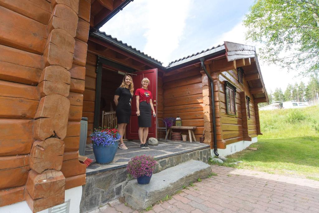 dos mujeres de pie en el porche de una cabaña de madera en Hytter Dombås, en Dombås