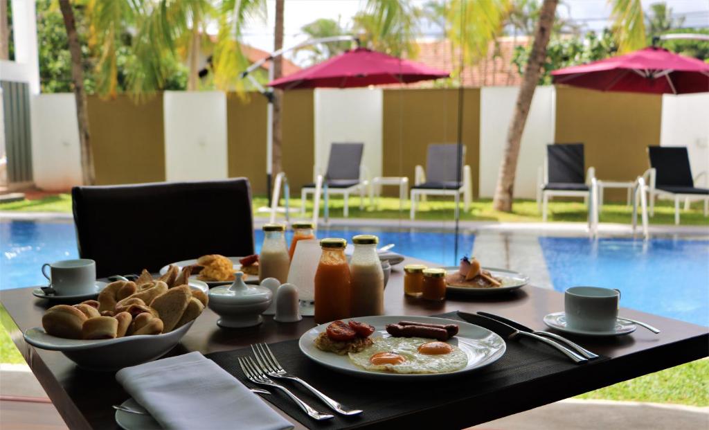a table with a plate of breakfast food on it at Daffodils Beach Negombo in Negombo