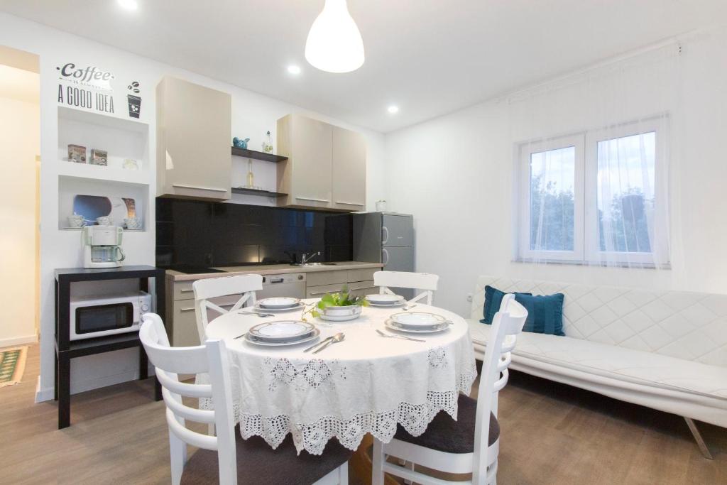 cocina y comedor con mesa y sillas en Apartmani Olivette, en Šibenik