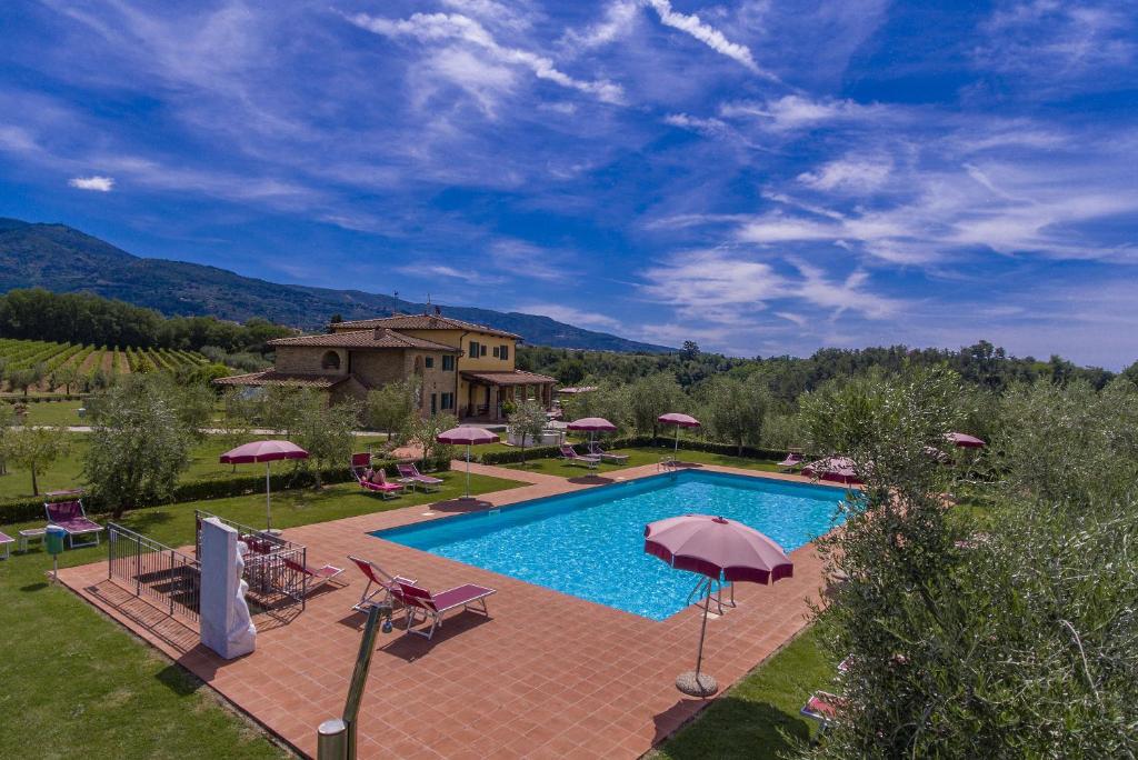 una piscina al aire libre con sombrillas y una casa en Savernano, en Reggello