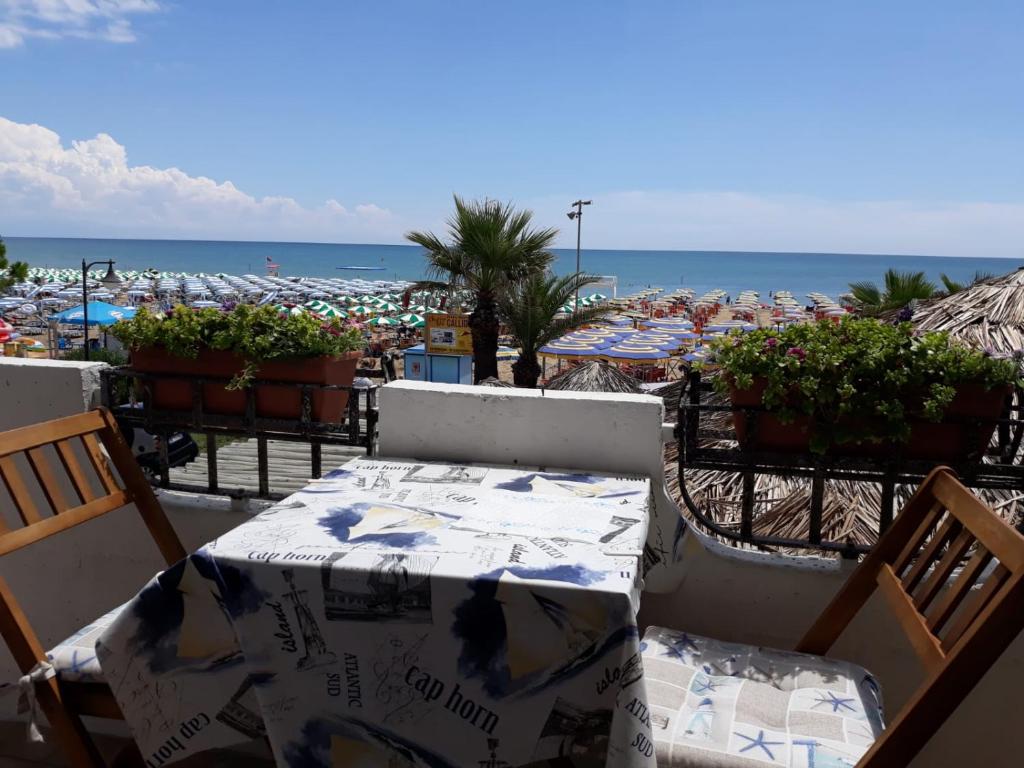 een terras met een tafel en stoelen en een strand bij Appartamento Frontemare Azzurra in Caorle