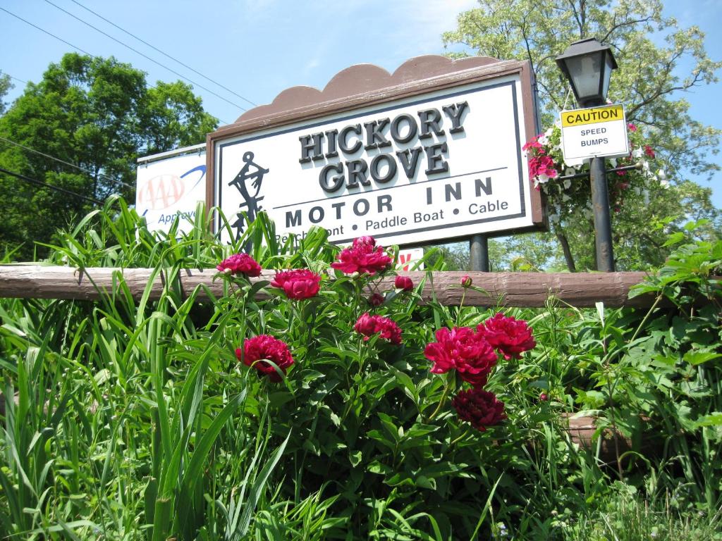 Una señal para el motel Hipper Grove con flores en Hickory Grove Motor Inn - Cooperstown en Cooperstown