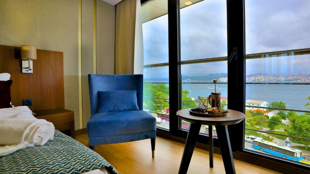 ein Schlafzimmer mit einem blauen Stuhl und einem großen Fenster in der Unterkunft Zimmer Bosphorus Hotel in Istanbul