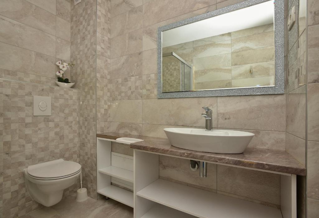 a bathroom with a sink and a toilet and a mirror at Holiday Home Ivan in Makarska