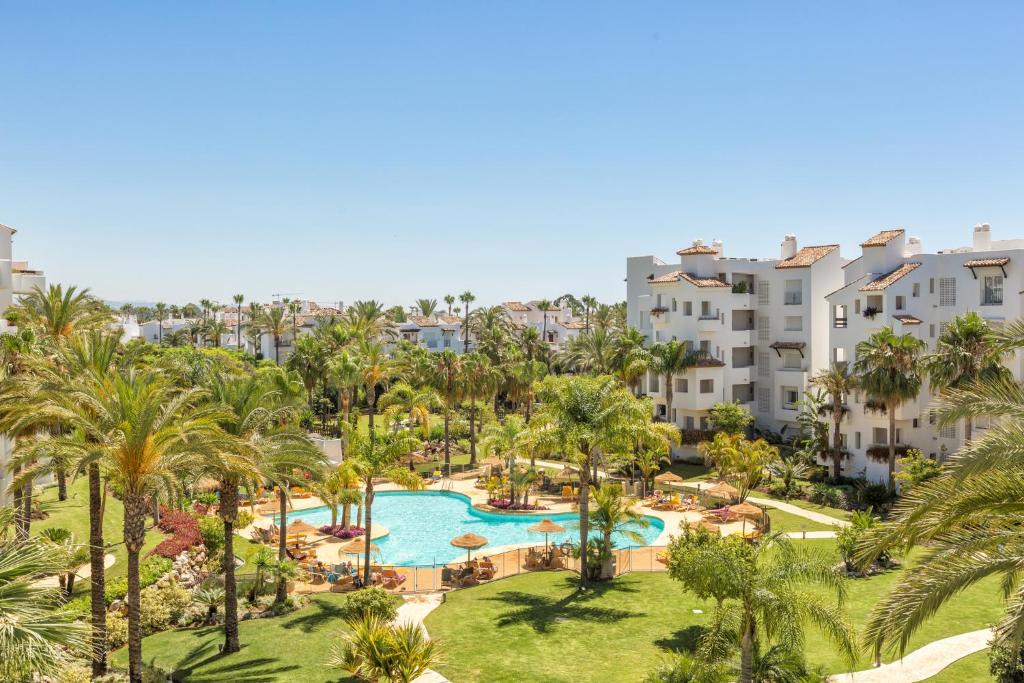 an aerial view of a resort with a pool and palm trees at Sea & mountain view penthouse in Estepona