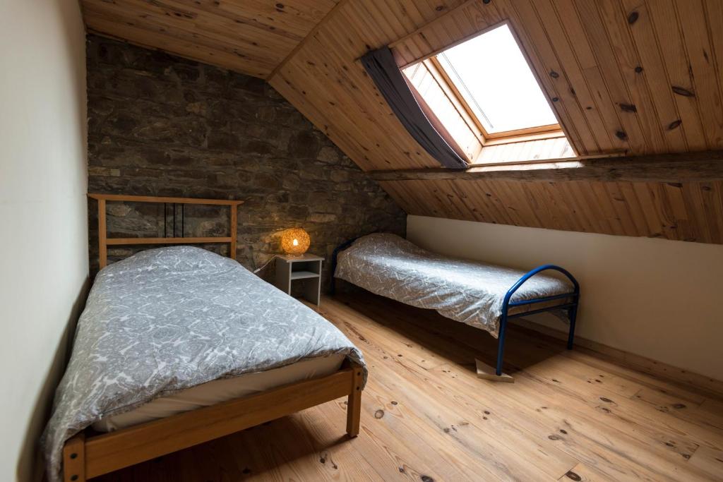 a attic bedroom with a bed and a window at Les Trois Voisins in Bourseigne-Vieille