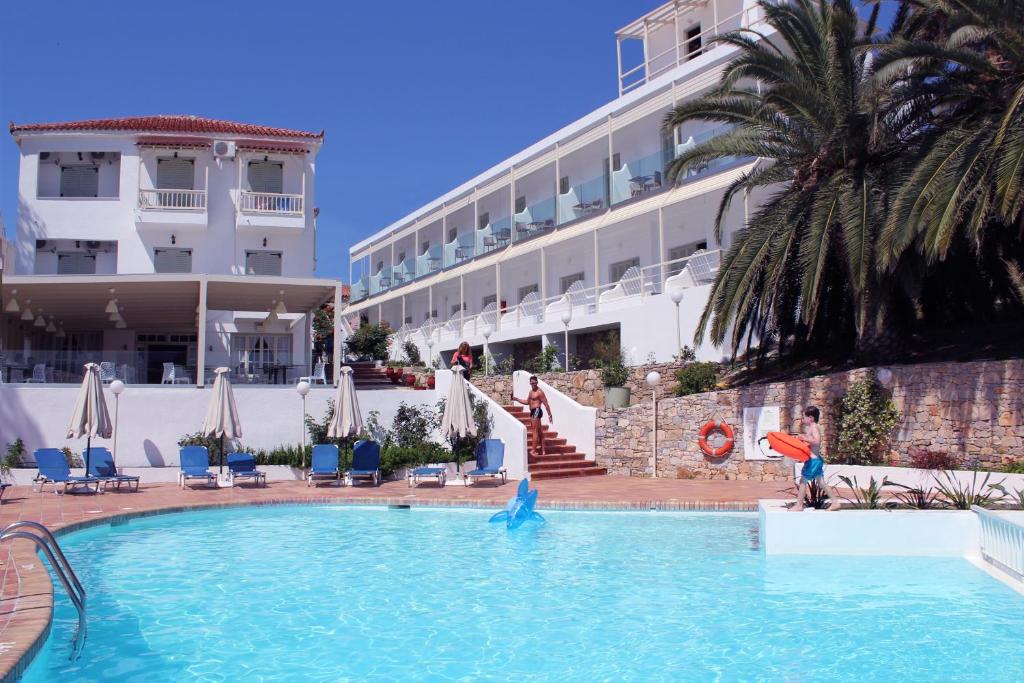 a swimming pool in front of a hotel with a dolphin in the water at Paradise Hotel in Patitiri