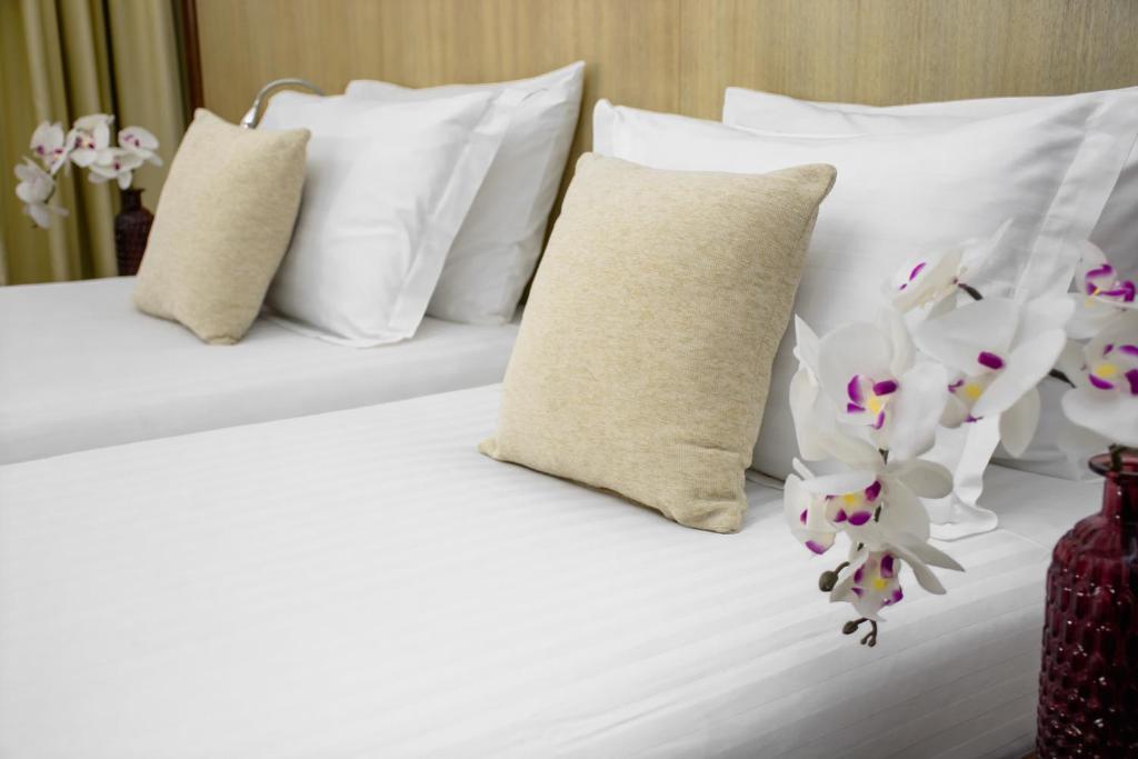 Una cama blanca con almohadas blancas y flores. en City5 ROOMS & SUITES by LSA, en Skopje
