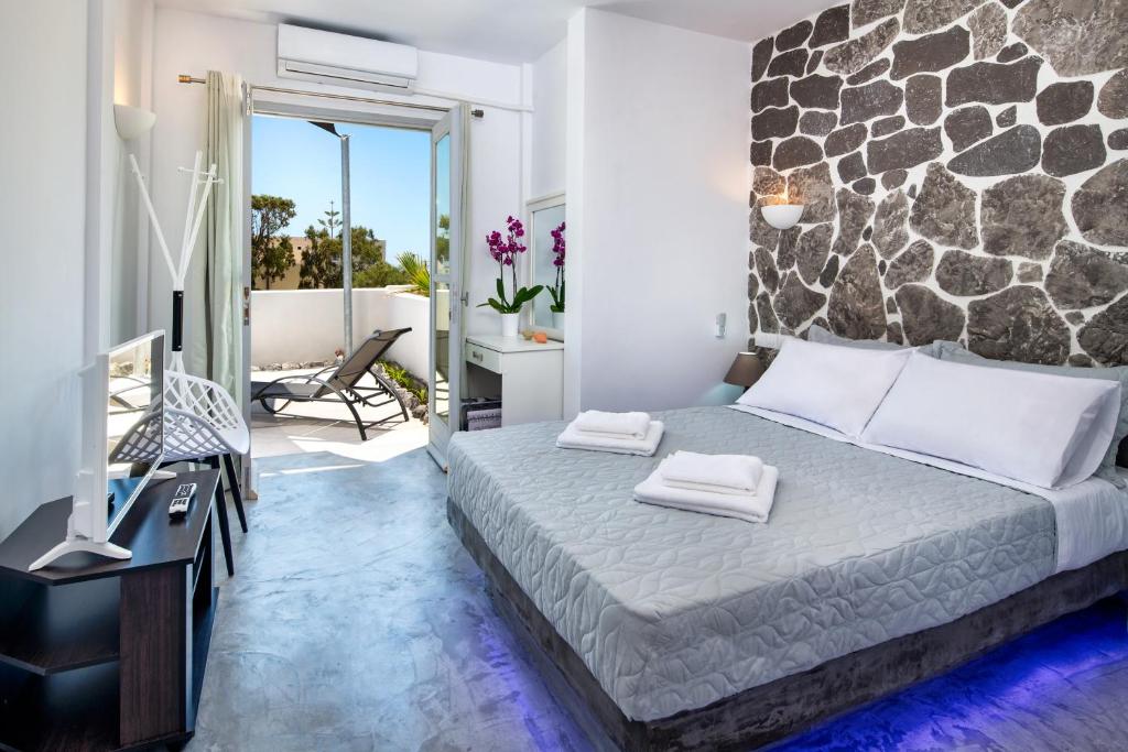 ein Schlafzimmer mit einem Bett mit einer Steinmauer in der Unterkunft Sun Springs Suites in Kamari