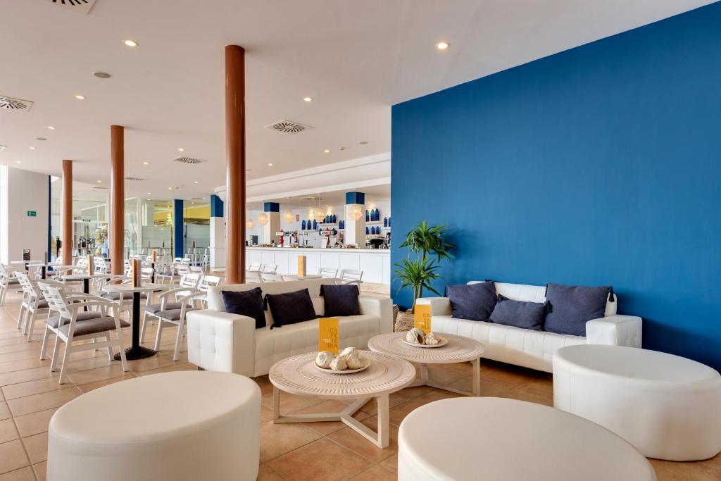 a lobby with white furniture and a blue wall at Garden Playanatural - Adults Only in El Rompido