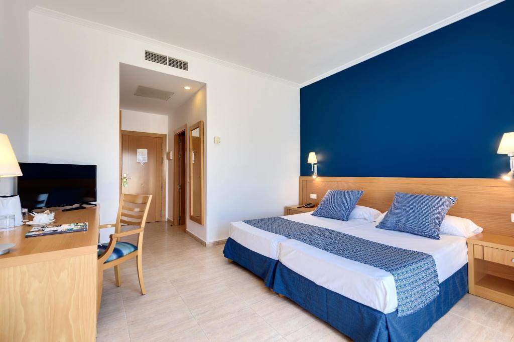 a hotel room with a bed with a blue wall at Garden Playanatural - Adults Only in El Rompido