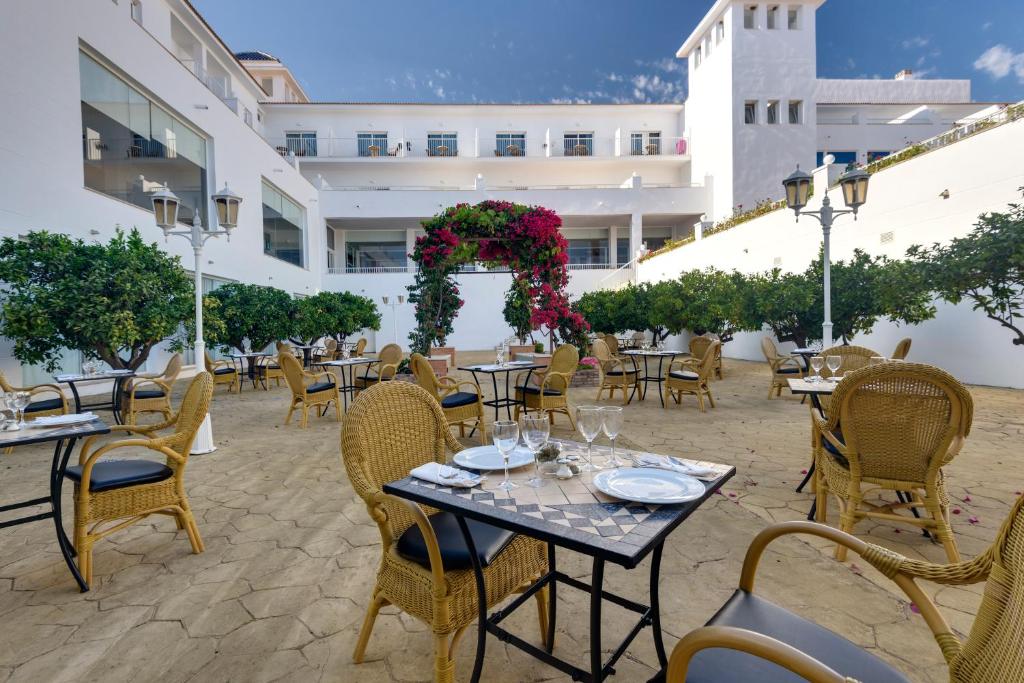 a patio with tables and chairs and a building at Garden Playanatural - Adults Only in El Rompido