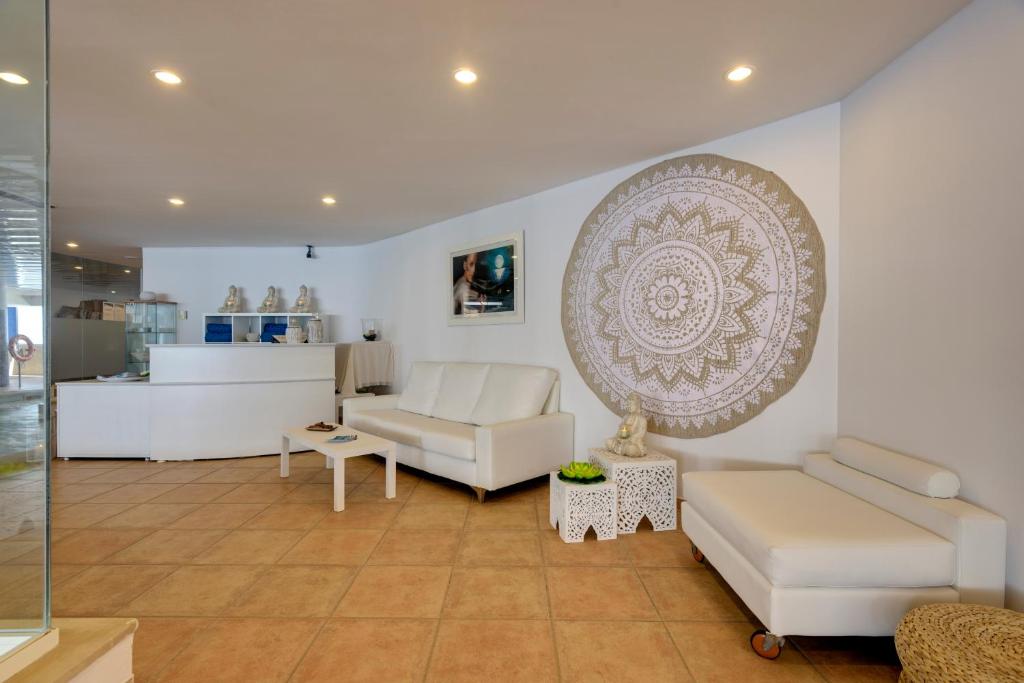 a living room with white furniture and a large plate on the wall at Garden Playanatural - Adults Only in El Rompido