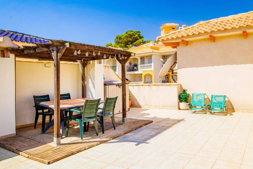 a patio with a wooden table and chairs on a house at Casa Roka in Campoamor