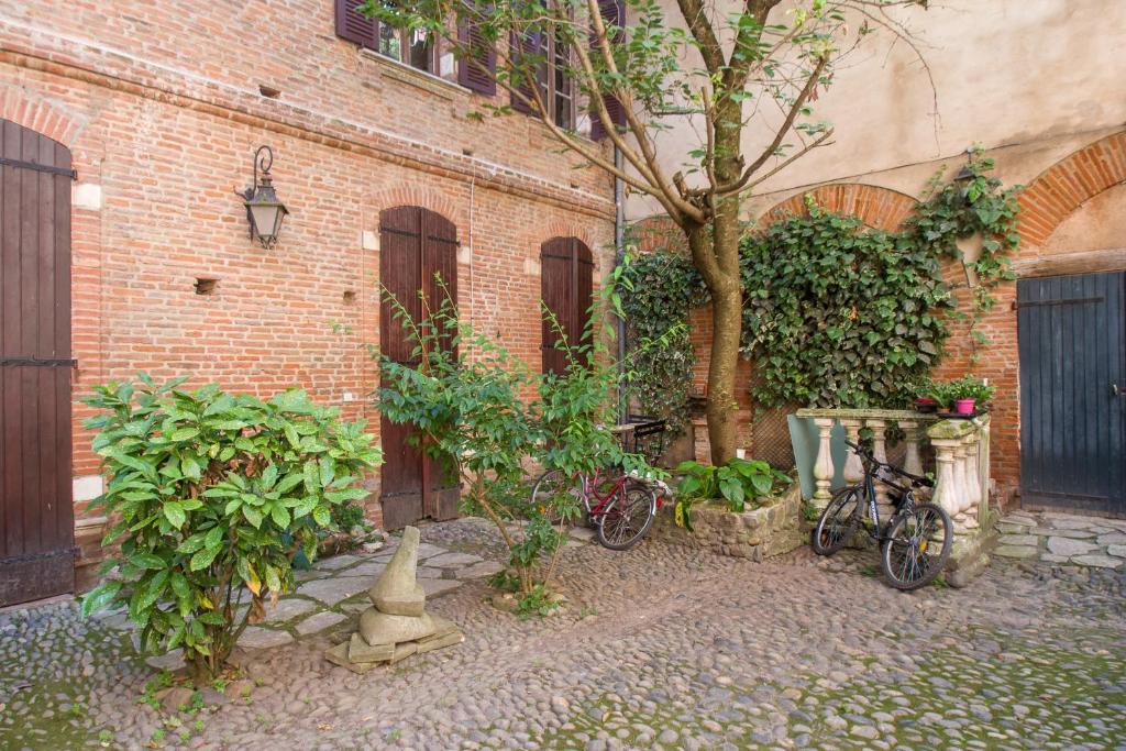 zwei Fahrräder, die neben einem Backsteingebäude mit einem Baum geparkt sind in der Unterkunft La Dame du Taur by Cocoonr in Toulouse