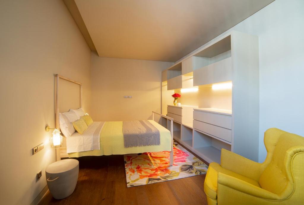 a small bedroom with a bed and a yellow chair at Casa com Alma Portuguesa @ Top Location Cais do Sodré in Lisbon