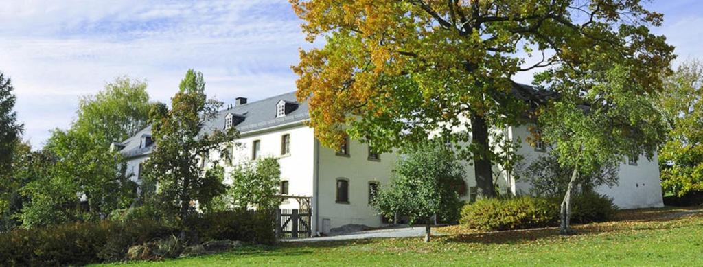Landhausgarten Bunzmann في Berg: بيت ابيض كبير وامامه اشجار