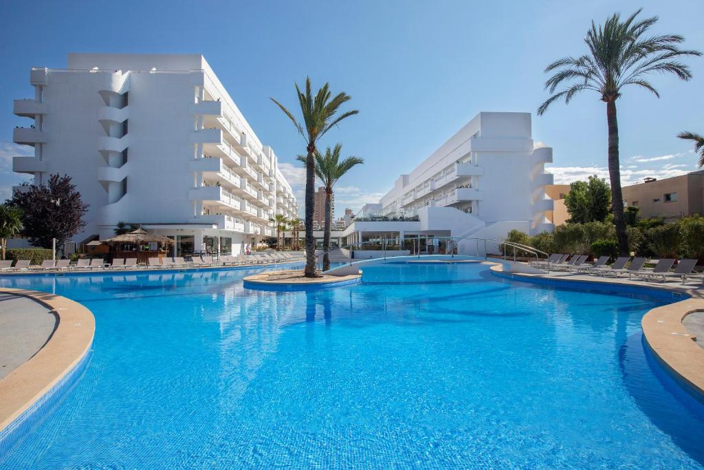 a large swimming pool with palm trees and buildings at HM Martinique in Magaluf