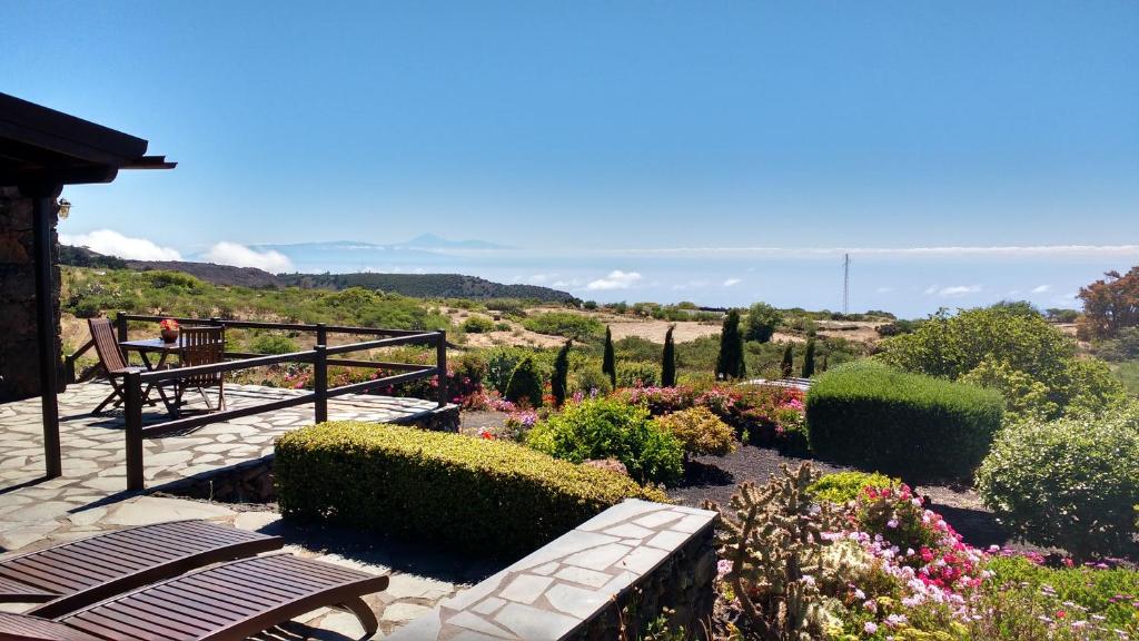 una panchina in un giardino con fiori e alberi di Casa Rural El Valle a San Andrés