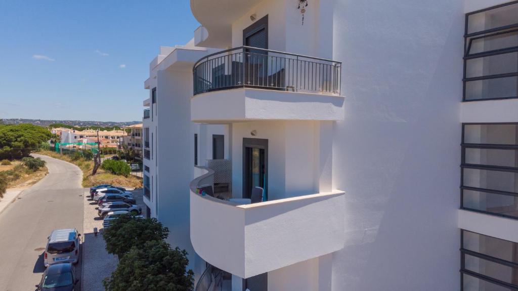 a white building with balconies and cars parked on a street at Vista das Ondas - 208 in Albufeira