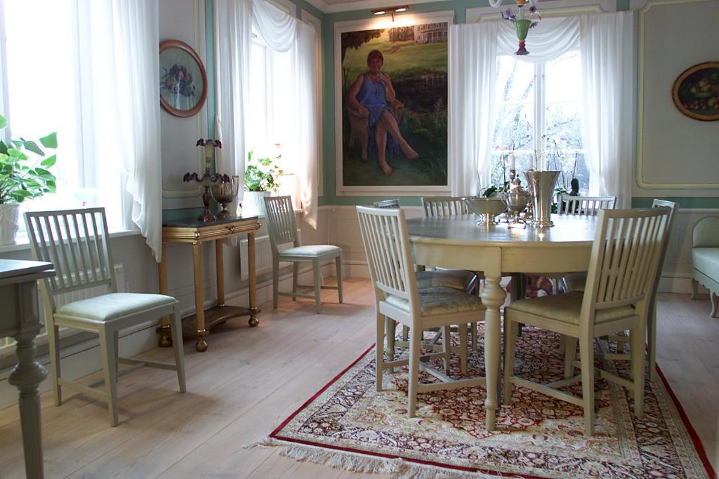 une salle à manger avec une table, des chaises et un tableau dans l'établissement Brunnbäcks Herrgård, à Mästerbo
