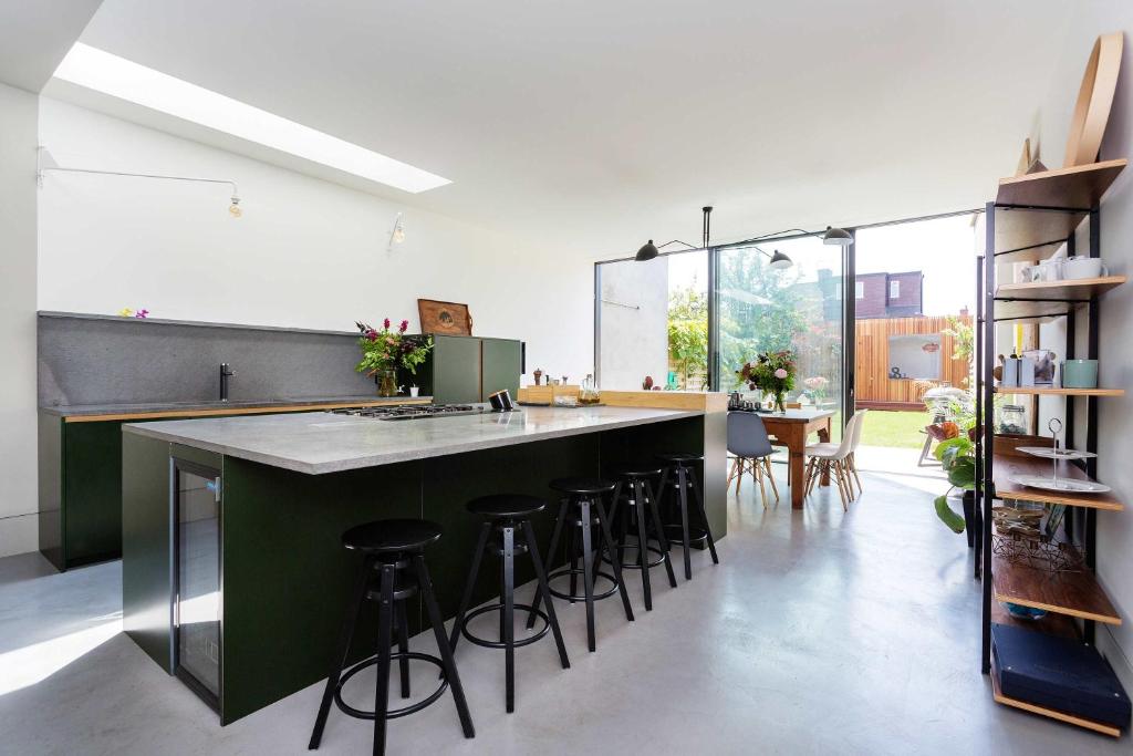 a kitchen with a green island with bar stools at Veeve - Kensal Rise Retreat in London