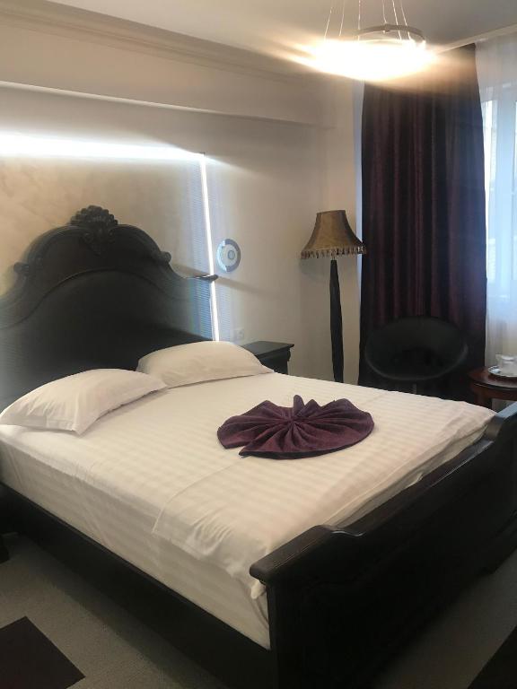 a bedroom with a large bed with a robe on it at Hotel Bulevard Prestige in Slatina