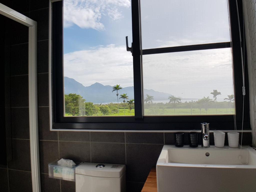 a bathroom with a window and a sink and a toilet at Taitung Jia Lulan Tribal in Taitung City