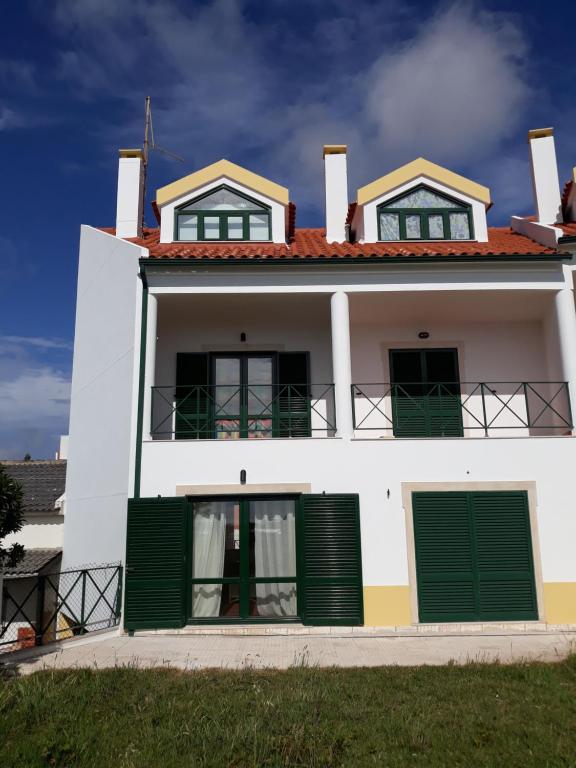 uma casa branca com persianas verdes e uma varanda em ZéLétte Beach House em São Bernardino