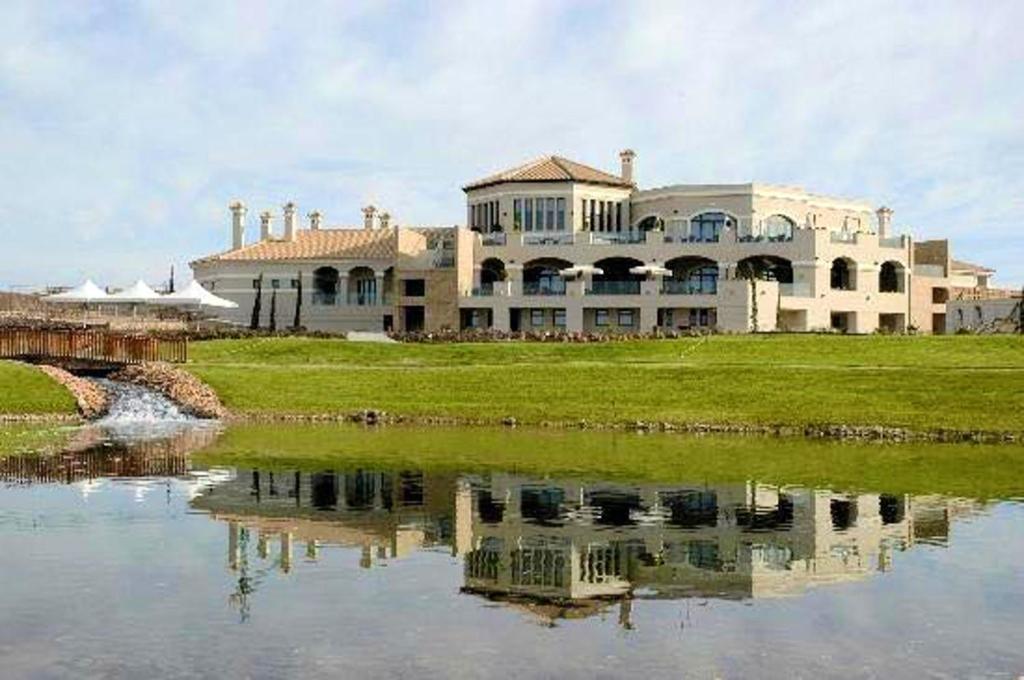 ein großes Haus neben einem Wasserkörper in der Unterkunft Hacienda del Alamo Golf in Fuente Alamo