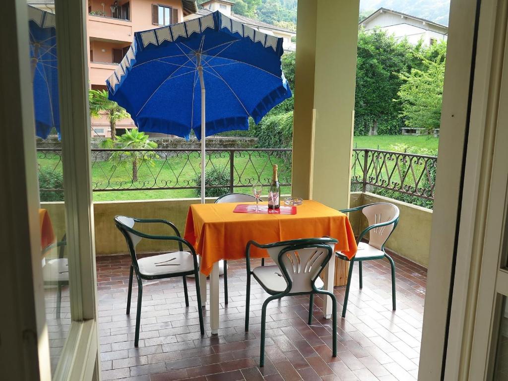 einen Tisch und Stühle mit einem blauen Sonnenschirm auf dem Balkon in der Unterkunft Sveva in Stresa