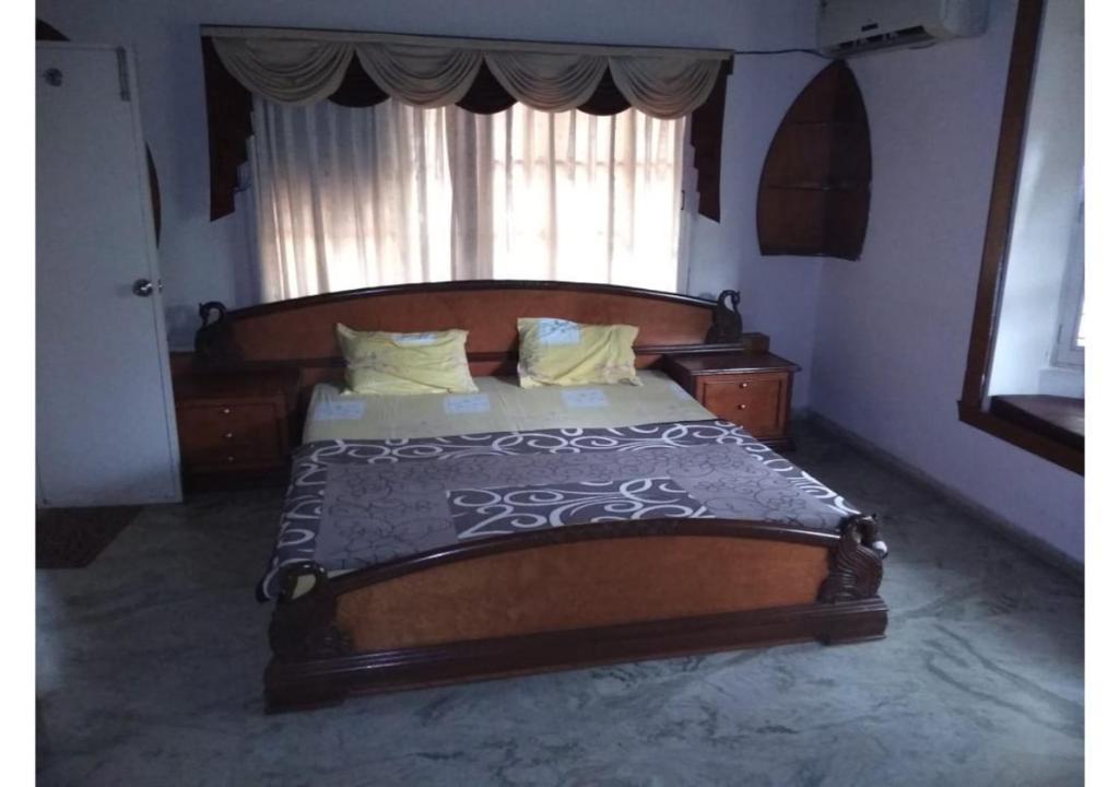 ein großes Holzbett in einem Schlafzimmer mit Fenster in der Unterkunft The Raj Villas in Mount Ābu