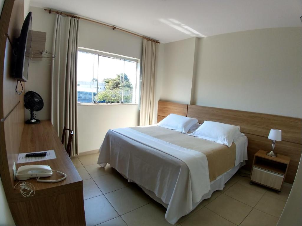 a hotel room with a bed and a window at Hotel Monte Carlo in São João del Rei