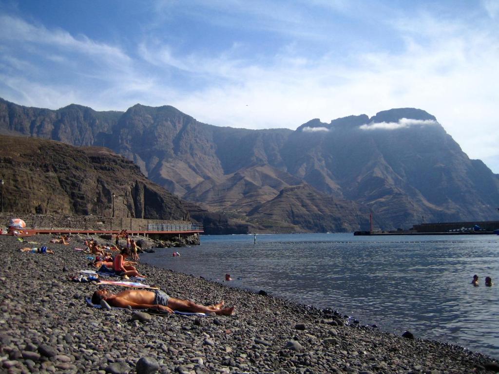 a group of people laying on a beach near the water at Apartamento Juli4 in Puerto de las Nieves