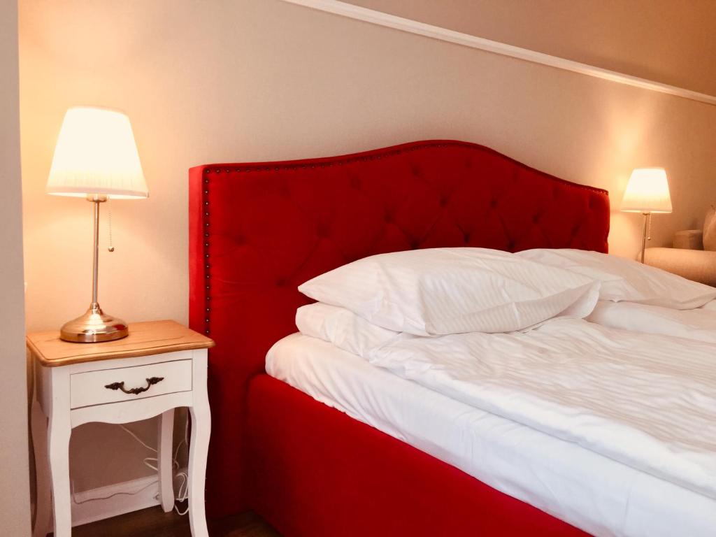 ミエンジズドロイェにあるApartamenty Międzyzdrojeのベッド(赤いヘッドボード付)、ナイトスタンド(ランプ付)