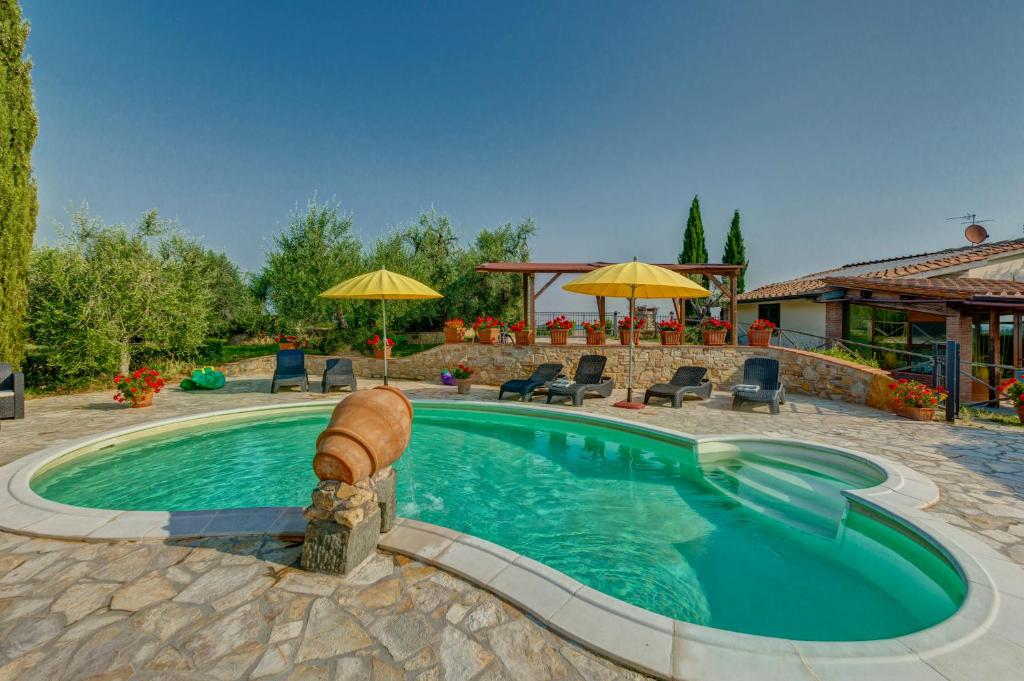 a swimming pool in a yard with chairs and umbrellas at La Villetta in Montaione