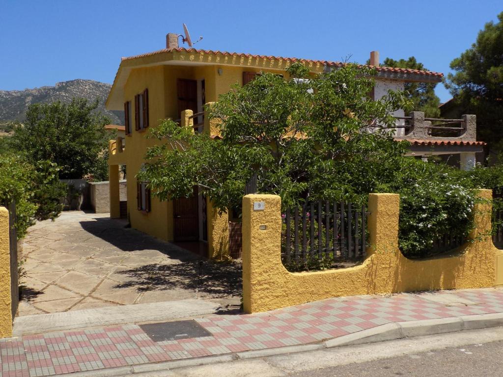 ein gelbes Haus mit einem Zaun davor in der Unterkunft Casa Vacanze Gardenia in Solanas