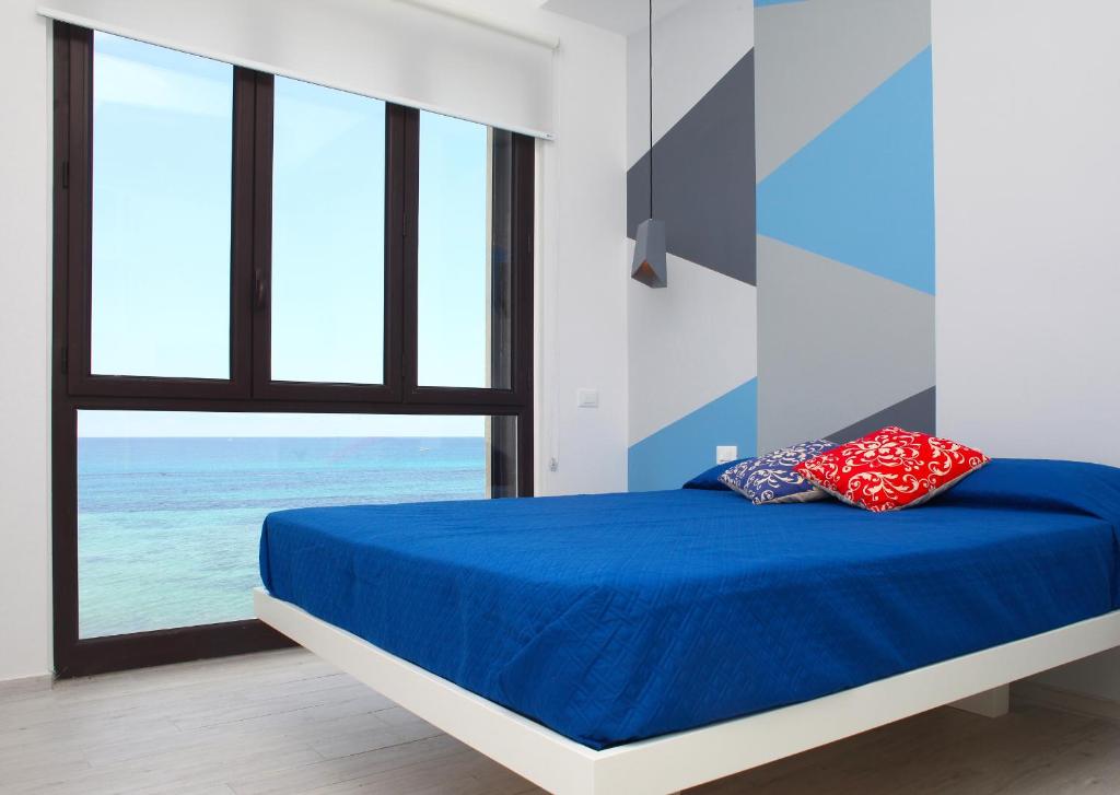 Schlafzimmer mit einem Bett mit blauer Bettwäsche und einem Fenster in der Unterkunft Sea Windows Suite in Trapani