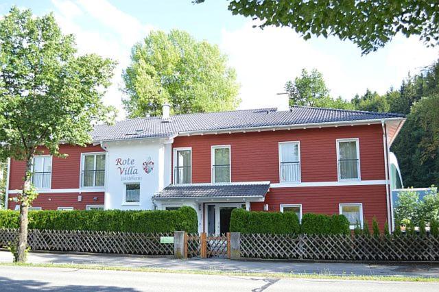 una casa roja y blanca con una valla delante en Rote Villa Füssen en Füssen