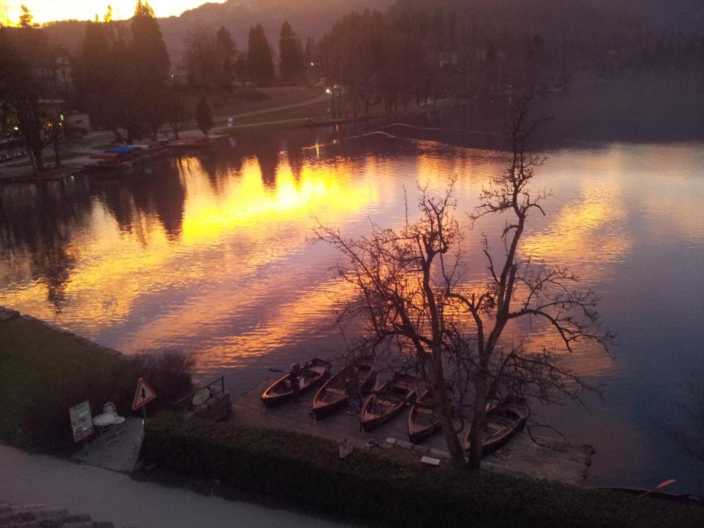 a group of boats sitting in the water at sunset at Pletna Lake View Apartment (Ground Floor) in Bled