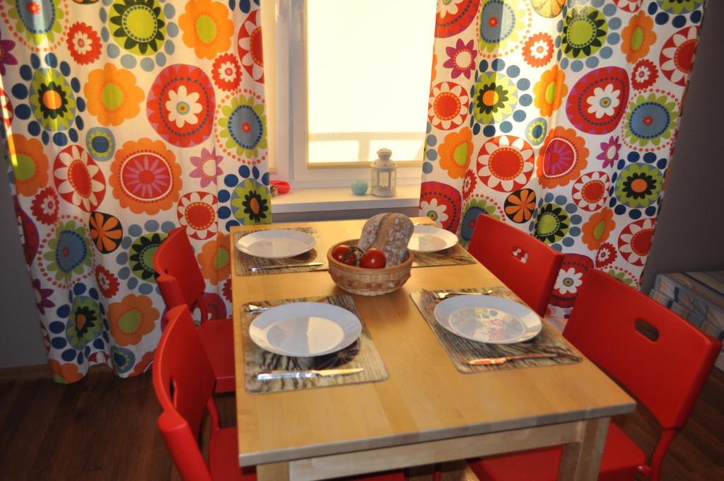 una mesa de madera con sillas rojas y una mesa con platos en Apartament Wrzos, en Dziwnówek
