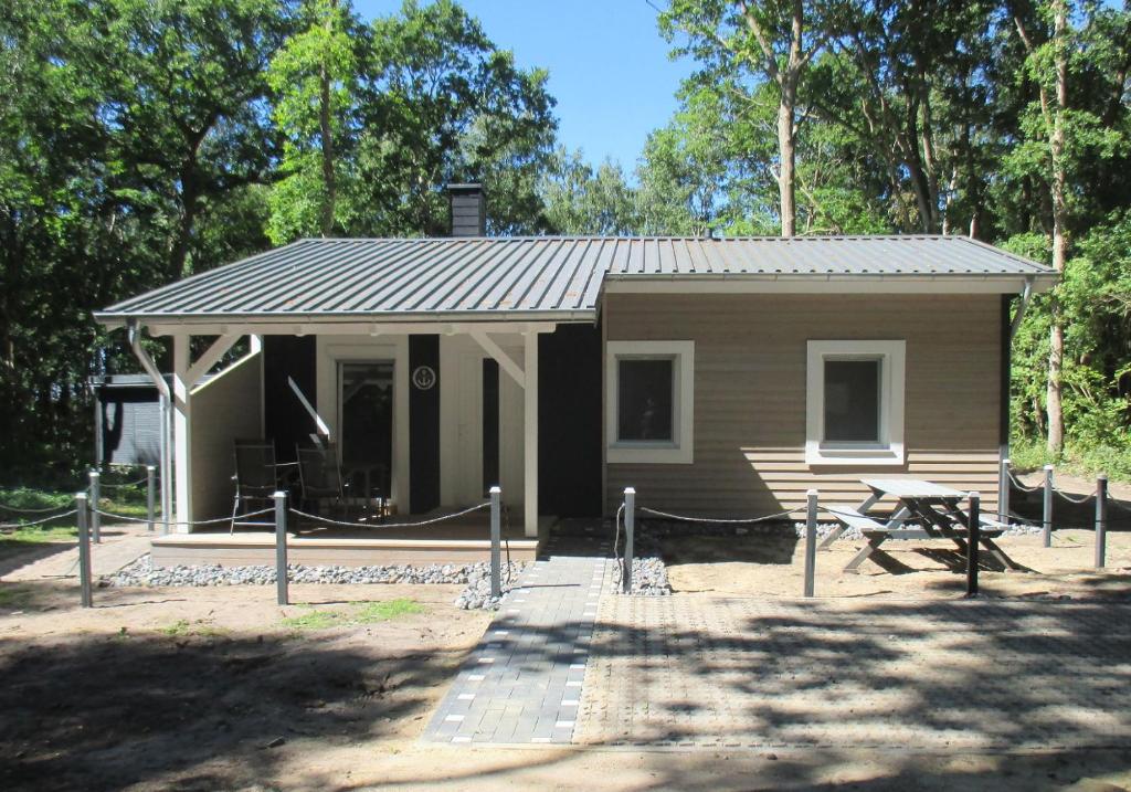 a small cabin with a picnic table in front of it at Strandhaus Vielmeer - exklusiv mit Sauna & Kamin direkt am Strand in Dranske