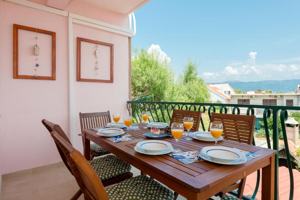 a wooden table with glasses of orange juice on a balcony at Apartment sea view Marija Franić in Slatine