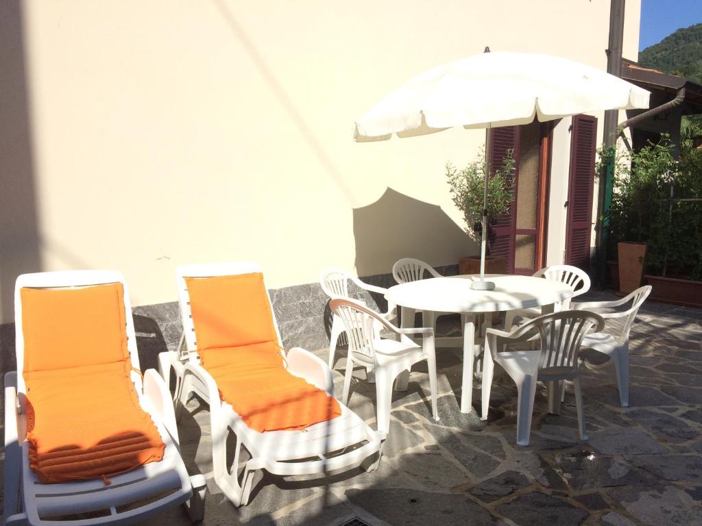 un patio con mesa, sillas y sombrilla en Casa Lorenzo, en Bellagio