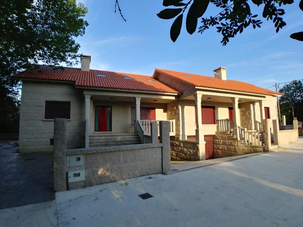 a house with a red roof on a street at Casa A Veiga in O Grove