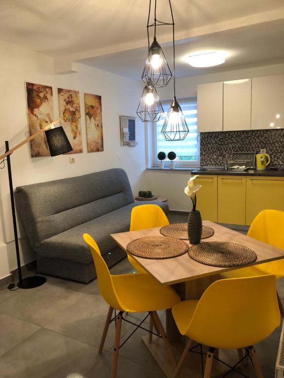 a kitchen and living room with a table and yellow chairs at Apartment Park in Osijek